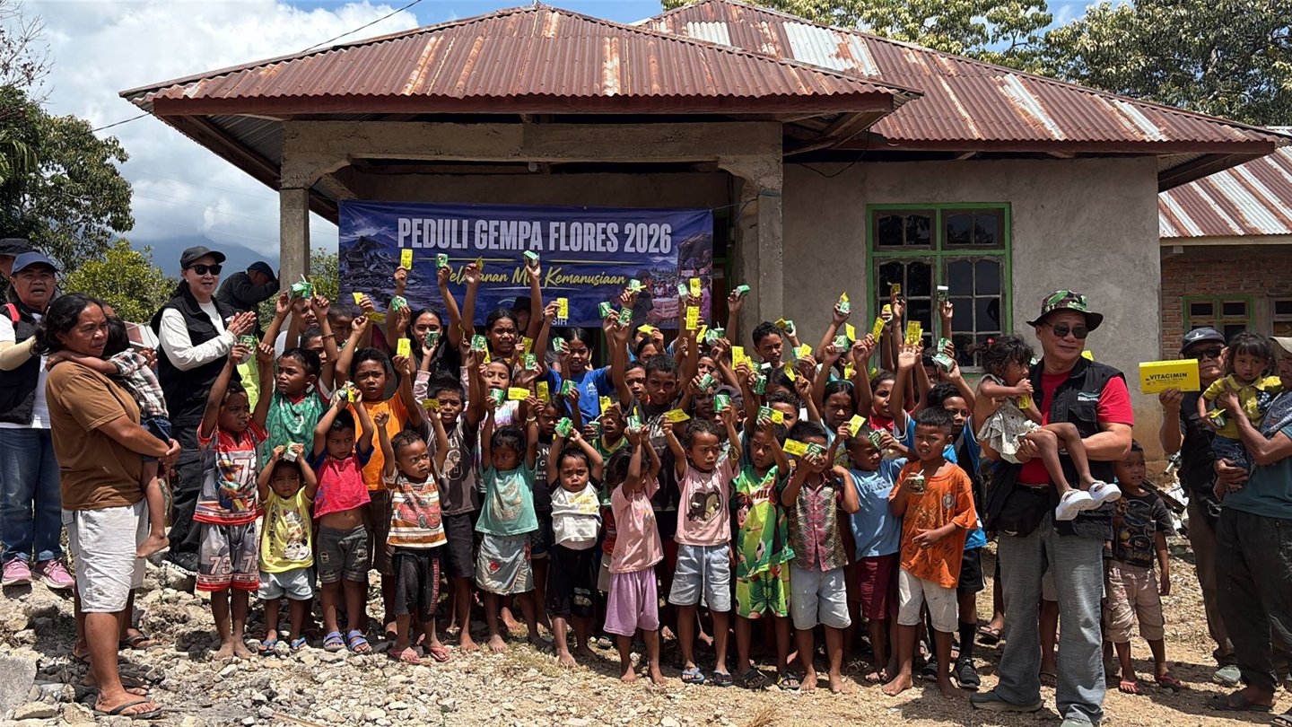Anak-anak dan warga berfoto bersama Tim Misi Kemanusiaan Yayasan Sungai Kasih di depan spanduk Peduli Gempa Flores 2026
